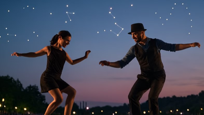 Deux personnes faisant des claquettes sur une scène avec en arrière plan des drones lumineux.